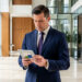 Un concierge professionnel consulte une tablette dans le hall moderne et lumineux d’une résidence.