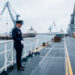 Agent de sûreté maritime en uniforme contrôlant les accès sur le pont d’un navire commercial dans un port français.